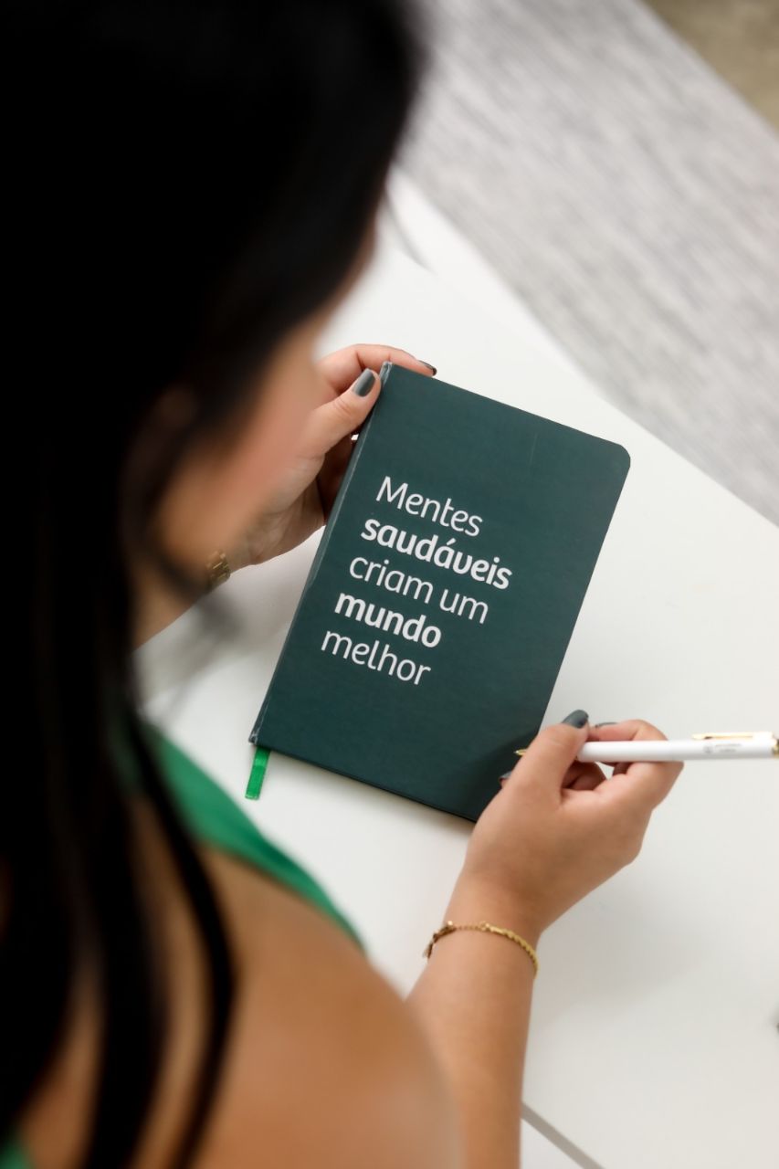 Viviane Collet escrevendo em caderno sobre mentes saudáveis